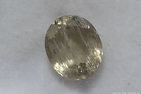 Close-up front view of a loose oval cut Zultanite gemstone on white background showing color and inclusions.