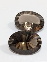 Close up of a single oval faceted smokey quartz gemstone showing detailed facets and light reflections.