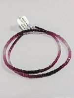 Close-up photo highlighting portion of the necklace with smaller faceted ruby beads showing bead shape and color detail.