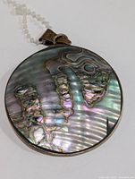 Front view close-up of the round abalone shell pendant with silver bezel and bail.