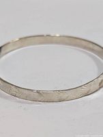 Close-up of the sterling silver bangle bracelet showing engraved pattern detail on the surface