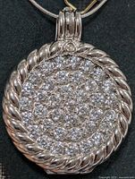 Close-up of twisted silver rope border pendant densely paved with clear cubic zirconia stones.