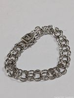 Front angled view of the silver double link chain bracelet laid flat on white surface showing the clasp and chain links.