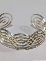 Front view of silver openwork bangle bracelet showing oval pattern.