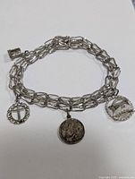 Sterling silver bracelet with three religious-themed charms displayed flat showing full length and charm details.