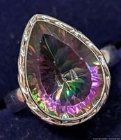 Close-up of a pear-shaped mystic topaz ring set in sterling silver with engraved detailing on the band.