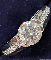 Close-up of 2.6ct moissanite center stone with two rows of small accent stones on silver band