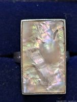 Front view of silver ring with rectangular mother of pearl inlay on a blue background.