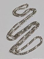 Image showing the full laid-out silver chain necklace, displaying the Figaro link pattern and overall length.