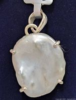 Front view close-up of the silver pendant showcasing the large irregular white pearl and silver prong setting.