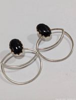 Two silver earrings with black onyx oval stones and geometric frames