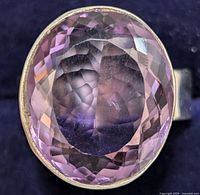 Close-up image showing detailed faceted oval amethyst set in silver band.