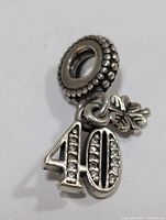 Silver Pandora style bead showing side with dangling '40' number and clover charms