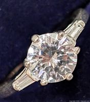 Close up image showing the round center cubic zirconia stone with baguette CZ stones on the sides and silver band.