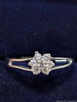 Front view of silver ring with flower-shaped cluster of clear CZ stones on split band.