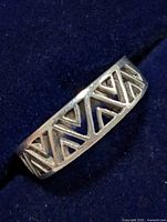Top angled view of silver ring with triangular cutout design in silver metal.