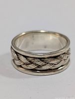 Close-up front view of silver ring showing braided pattern around middle.