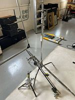 Two chrome C-stands with legs splayed, gobo arms and grip heads on concrete floor