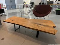 Front view of live edge tabletop showing natural wood grain, knots and metal sled legs.