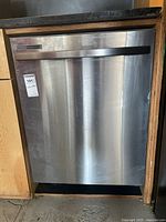 Front view of stainless steel Samsung dishwasher installed under countertop, door closed with horizontal handle.