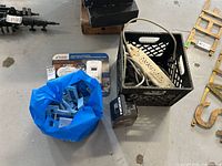 Wide view showing bag of light switches, Noco battery charger in box, Kidde CO detector in packaging, and power strips in plastic crate.
