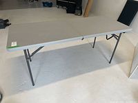 Full view of the gray plastic folding table set up with metal legs extended.