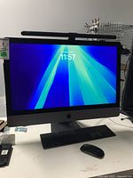 Front view of iMac Pro powered on, LED monitor light bar attached, keyboard and mouse on desk