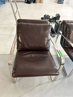 Front view of one chair showing chrome frame and dark brown leather seat and back cushions