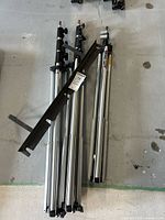 Three silver aluminium light stands laid on concrete floor