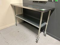 Front-left view of stainless steel table showing work surface and lower shelf