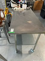 Angled front view showing tabletop surface, left-side casters, lower shelf