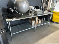 Frontal view of entire stainless steel table with lower shelf and items on top
