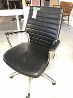 Black vinyl padded office chair with horizontal stitched backrest and seat, metal frame and armrests with padded black vinyl, on caster wheels.