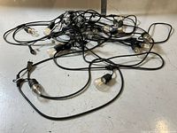 Photo showing tangled black wire string lights with clear round bulbs spaced along the cord, bulbs have LED filament inside.