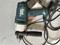 Black & Decker drill model DR600 showing body, venting, and handle with attached auxiliary handle and power cord.