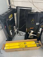 Two Vista Beam 300 units leaning against wall with box of fluorescent tubes at base