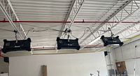 Three black rectangular fixtures hanging from ceiling grid