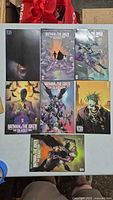 Top view of all 7 comics laid out showing cover art featuring Batman and The Joker.