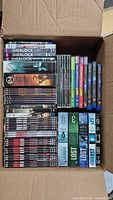 Top view of DVD and Blu-ray TV series in cardboard box including Sherlock, 24, Criminal Minds, Lost seasons.