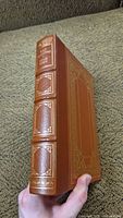 Angled view of the book showing thickness, leather spine, and embossing.