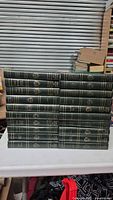 Stack of 20 green hardcover Harvard Classics books with gold embossed spines arranged on white surface