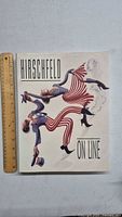 Front cover of Hirschfeld On Line art book laid next to a ruler for size reference.