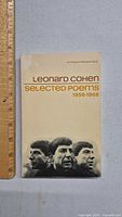 Front cover of Leonard Cohen Selected Poems 1956-1968 showing title, author and images of Leonard Cohen with a ruler for size reference.