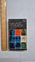 Front cover of the book 'Man and His Symbols' by Carl G. Jung with ruler for size reference
