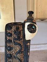 Side close-up showing white shell body with floral brass rosette and turquoise inlay