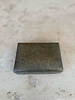 Closed view of the rectangular brass box showing the intricate hand engraved Middle Eastern patterns on the top surface.