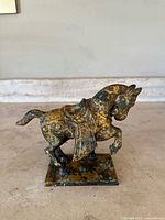 Front and side view of antique cast iron Tang Dynasty horse statue, showing detailed saddle and scarf embellishments.