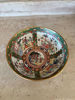 Top view of the porcelain bowl showing the intricate Famille Rose decorations with geisha scenes and floral designs.