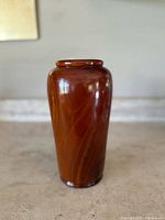 Front view of the tall cylindrical polished wood vase showing the smooth grain pattern and glossy finish.