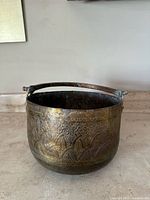 Front angled view of the antique hammered copper pot showing detailed hammered design and heavy handle.